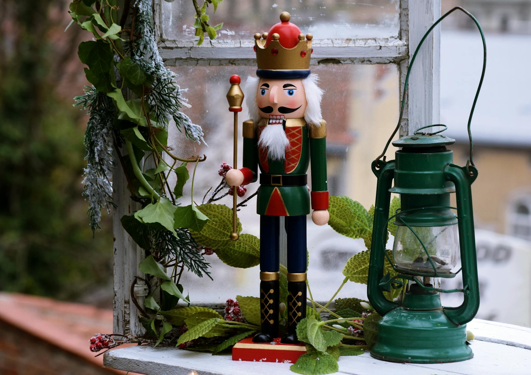 green red and brown nutcracker beside green lantern and plant